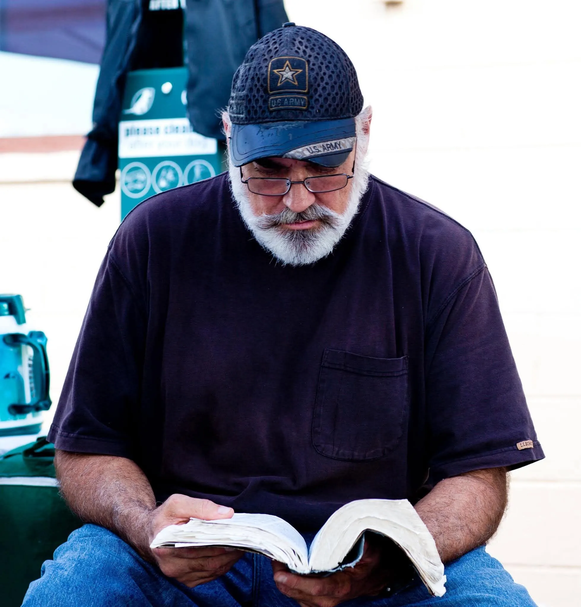 A man in a U.S. Army cap reading from a worn Bible