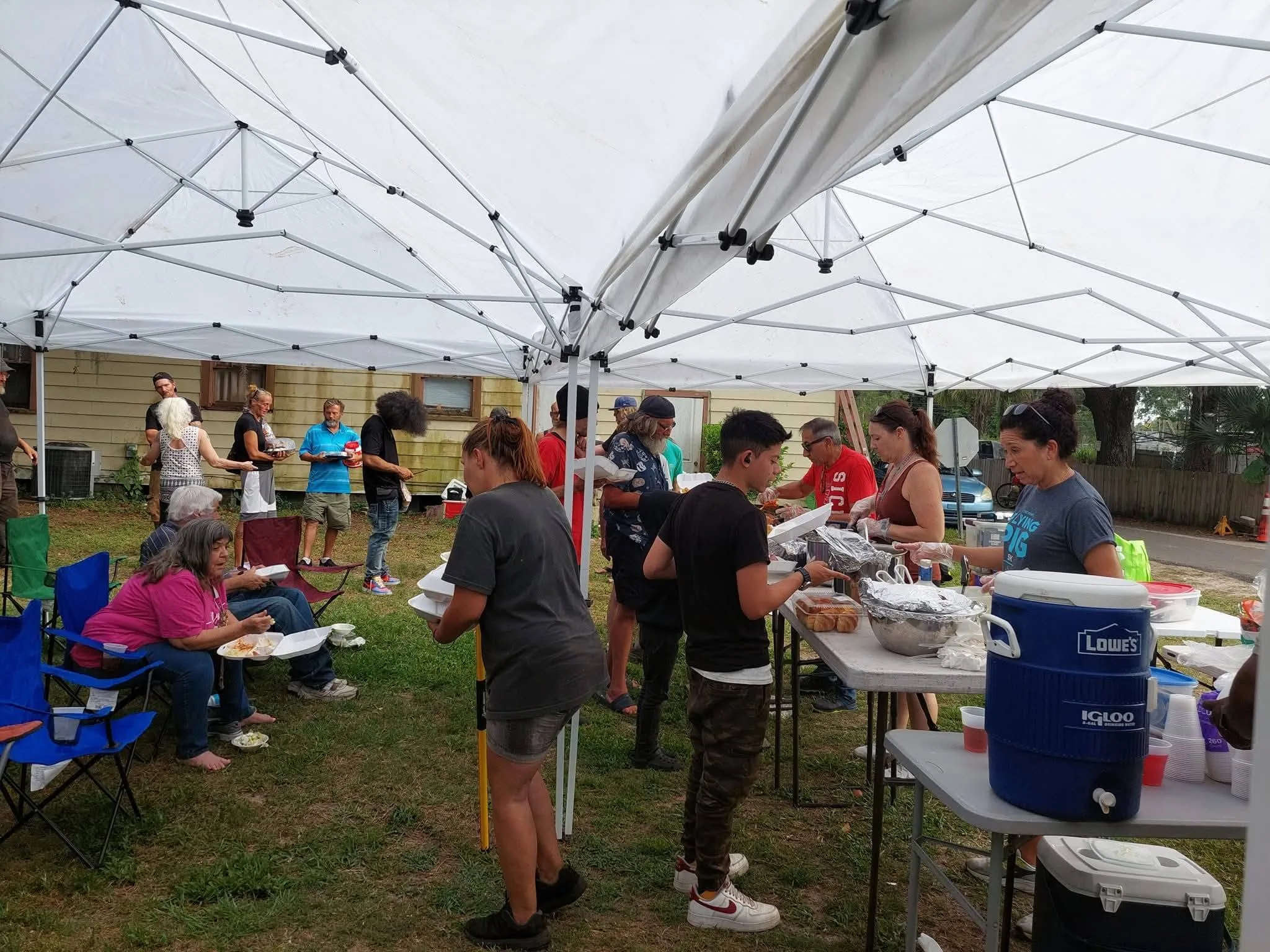 Volunteers serving food at a long outdoor table