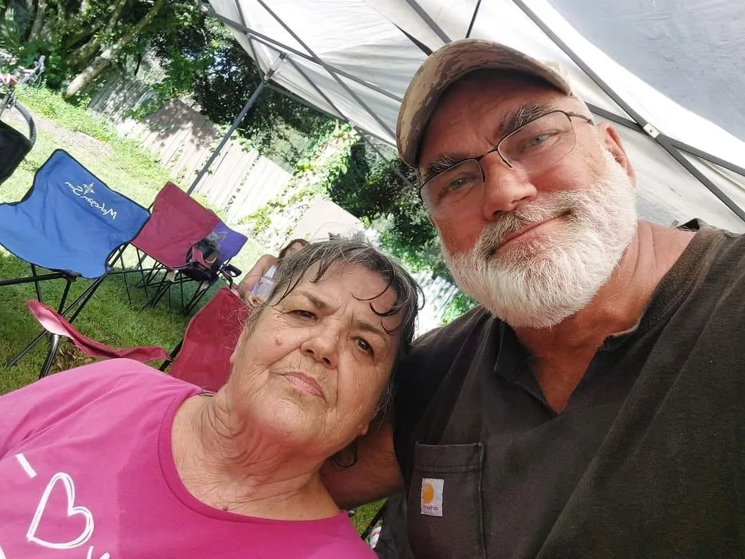 Two people leaning together in a selfie under a tent