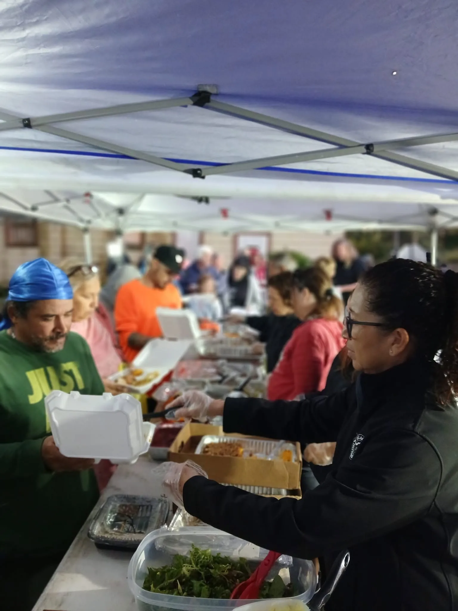 A volunteer handing a hot meal to a man in line